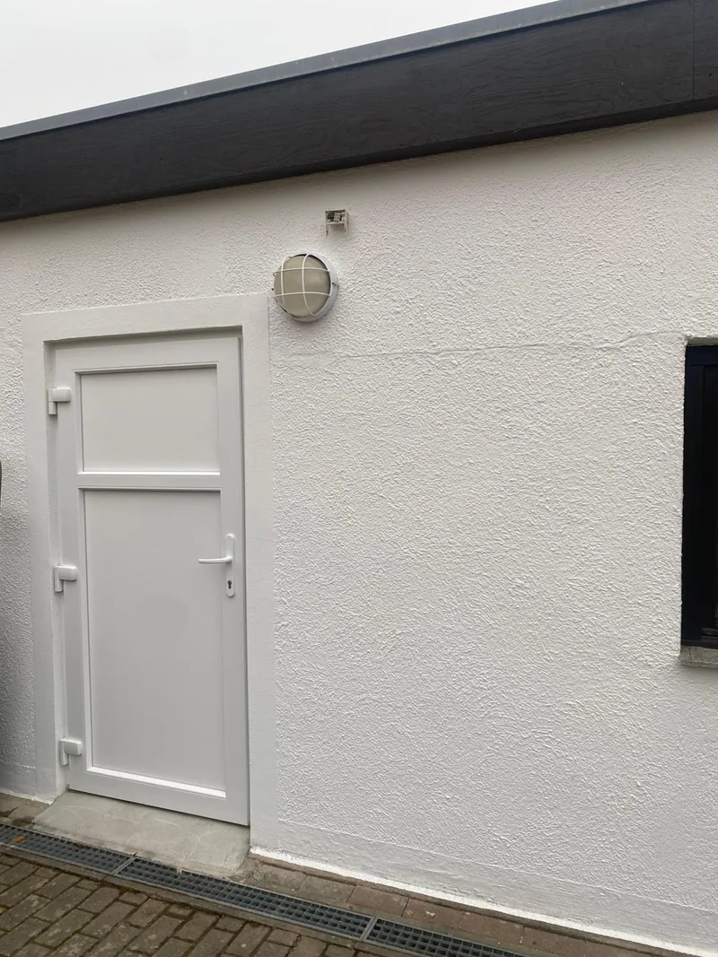 Neu eingebaute weiße Außentür an einem Wohnhaus