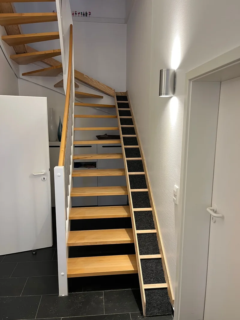 Offene Holztreppe mit Wandbeleuchtung, Seitenansicht